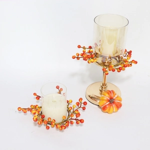 Close-up of fall orange berry candle rings on tabletop and metal candle holder base
