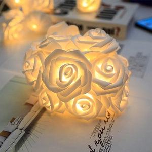 Close-up of white rose LED string lights with warm yellow glow for home decoration