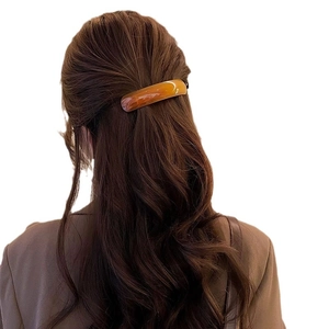 Amber tortoiseshell acetate spring hair clip shown on dark brown long wavy hair