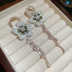 Gros plan de boucles d'oreilles fleurs dorées avec pétales en tulle et perles élégantes