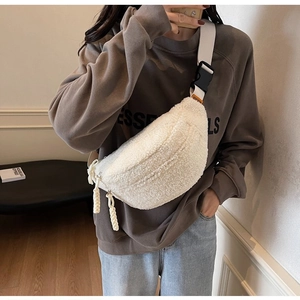 Detail of cream plush crossbody bag with woven zipper pull and adjustable strap