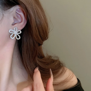 Close-up of sparkling flower stud earring with rhinestones on model's earlobe