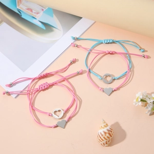 Vista detallada de pulseras tejidas rosa y azul con dijes de corazón de acero inox