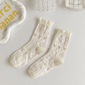 Detail of ruffle cuffs and pink bow pattern on cream white ribbed mid-calf socks