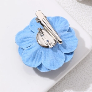 Detail view of the metal safety pin and duckbill clip on the blue denim camellia brooch