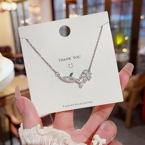 Detail of silver pearl necklace with zircon flower and leaf charms on display card