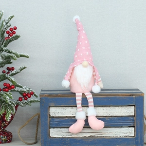 Dettaglio di gnomo natalizio in maglia rosa con paillettes seduto su una scatola di legno