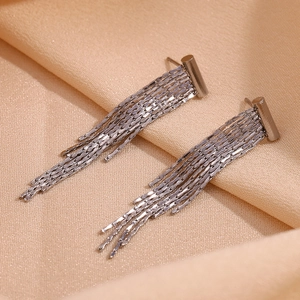 Macro shot of long silver chain tassels on earrings over elegant satin fabric