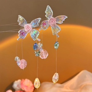 Detailed macro of colorful butterfly earrings with pink rose and beaded tassel accents