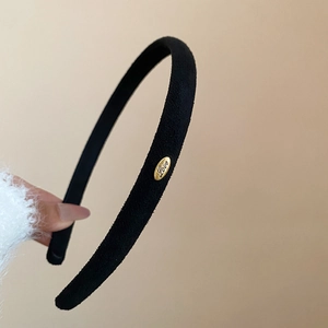 Détail d'un serre-tête en velours noir avec un petit médaillon ovale doré gravé Love