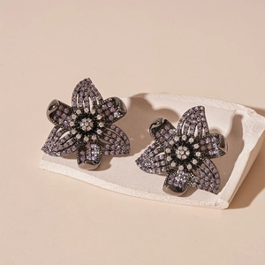 Macro detail of retro flower earrings with purple and white zircon crystals on stone base