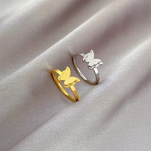 Minimalist titanium steel butterfly rings in gold and silver on grey silk fabric