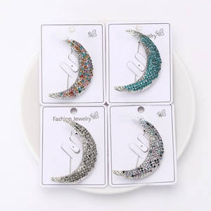 Detail view of four crescent moon brooches in multiple colors on white display card