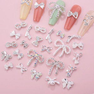Detailed view of silver alloy bow nail charms with pearls and rhinestones on colorful tips