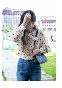 Close-up of a blue denim quilted shoulder bag styled with a polka dot bow blouse