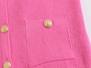 Detail of pink knit cardigan showing golden crown crest buttons and textured pocket fabric