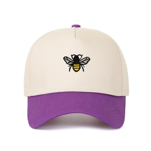 Detailed close-up of bee embroidery on a two-tone cotton twill trucker hat crown