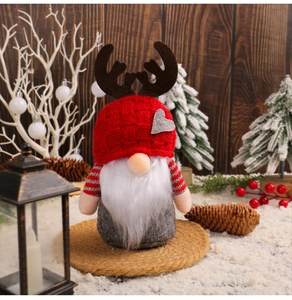 Close-up of Christmas gnome with red antler hat and heart decor in snowy scene