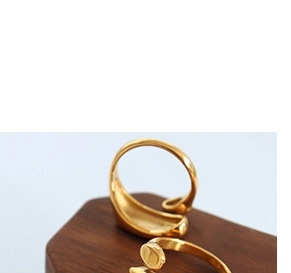 Close-up of elegant gold plated adjustable rings on a premium wooden display stand