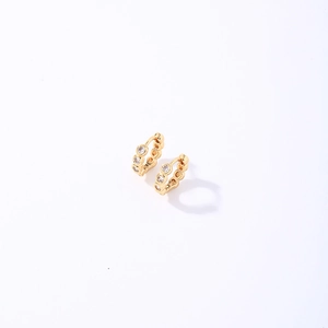 Minimalist gold huggie earrings with three inlaid cubic zirconia on a white background