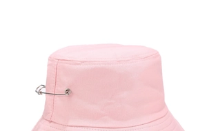 Détail d'un chapeau bob rose en coton avec une grande épingle de sûreté en métal argenté