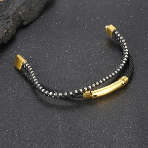 Detail of black woven leather bracelet with gold metal tubes and silver bead accents