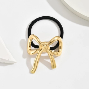 Minimalist gold alloy bowknot hair tie with elastic black band on a white stone background