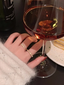 Close-up of gold double-layer bow ring and sparkling cubic zirconia ring on finger
