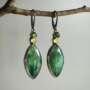 Pendientes vintage con gemas verde oliva en forma de gota sobre rama de madera natural