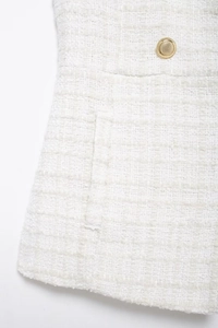 Detail of white tweed skirt featuring ornate golden buttons and side pocket texture
