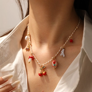 Detail of sweet pastoral necklace with cherry, mushroom, and floral charms on a model