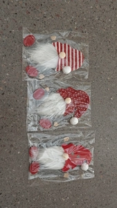 Detailed view of three Christmas gnome cutlery holders in red, white and grey plush fabric