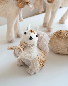 Close-up of a cream squirrel ornament with gold glitter and a knitted mini scarf