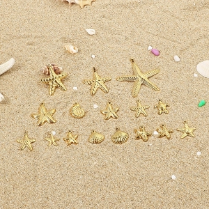 Golden stainless steel ocean charms with starfish and shells on a sandy beach background