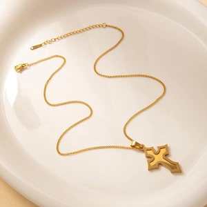 Detalle de collar de cruz en acero dorado con cierre de langosta y placa logo
