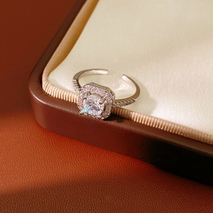 Macro shot of silver zircon flower halo open ring on silk and brown leather textures