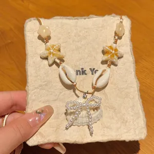 Detail of seashell and ceramic starfish necklace with a pearl bow on a braided cord