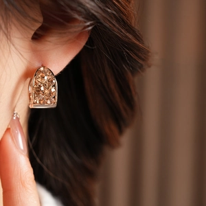 Détail macro de boucles d'oreilles vintage en forme de U avec strass champagne étincelants