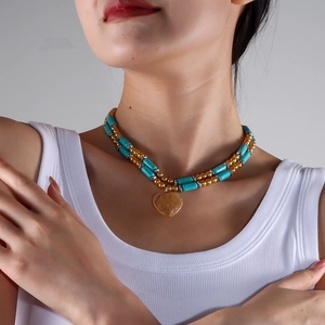 Detail of double-layer beaded necklace featuring turquoise accents and yellow heart pendant