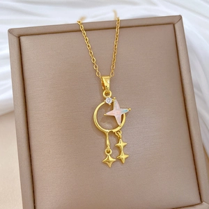 Detail of gold moon and star tassel necklace with opal stone on beige jewelry box