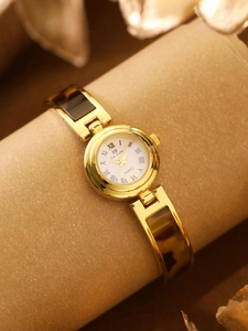 Detail of gold bracelet watch with amber tortoise shell pattern and white Roman dial