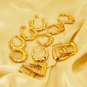 Set of golden bow and twisted hoop earrings displayed on yellow silk fabric background