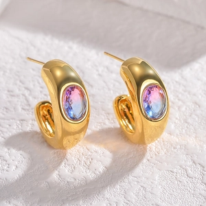 Macro detail of C-shaped gold earrings with gradient heart-shaped gemstones