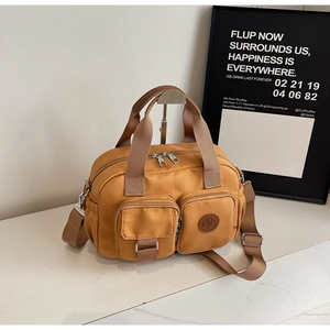 Detail der gelben Nylon-Handtasche mit zwei 3D-Fronttaschen und verstellbarem Gurt