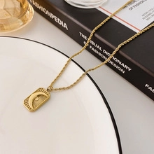 Detailed shot of golden rectangular pendant with moon and star engraving on rope chain