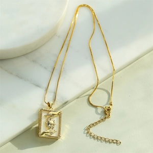 18K gold plated necklace with sun motif shell pendant on white marble background
