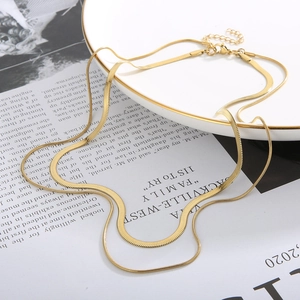 Detail of a double-layered golden flat snake bone chain with lobster clasp and extender