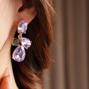 Close-up of vintage geometric teardrop earrings with purple rhinestones on a model