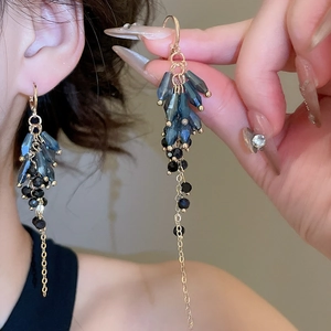Close-up of Bohemian crystal drop fringe earrings with gold chains and blue beads