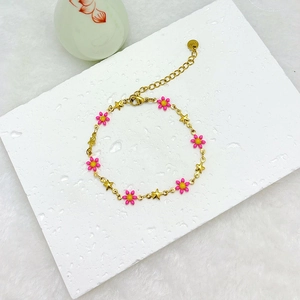 18k gold plated stainless steel bracelet with pink daisy and star charms on stone surface